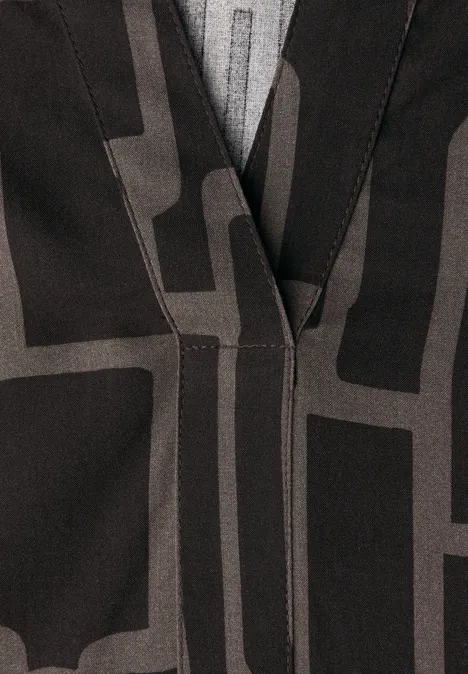Nahaufnahme eines schwarzen Blazers mit grauem, abstraktem geometrischem Muster.